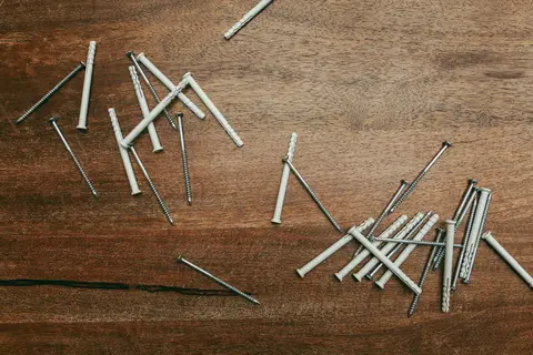 Close-up of nylon anchors and screws scattered on a wooden surface, perfect for DIY projects.