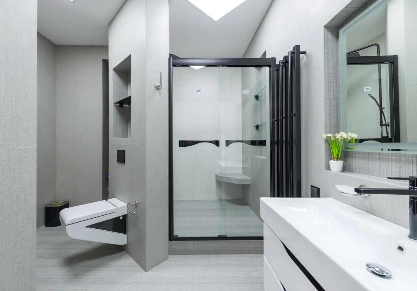 Sink with tap placed at wall with mirror in light spacious bathroom with toilet and glass shower cabin in apartment