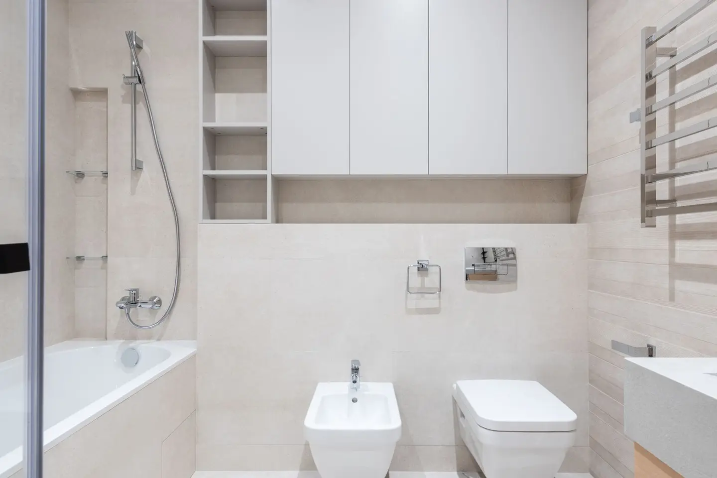 Interior of modern light bathroom with bidet and toilet next to sink and bath