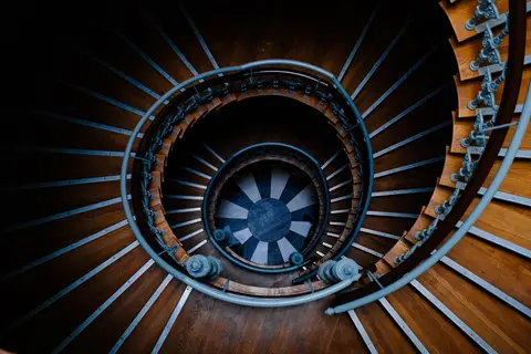 A top view of an elegant spiral staircase made of wood and metal, creating a captivating abstract pattern.