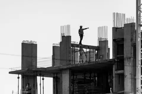 Silhouette of construction workers on a building site with one pointing towards the distance.