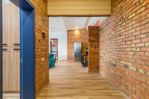 Spacious contemporary interior featuring brick walls and wooden flooring, blending modern and rustic design.