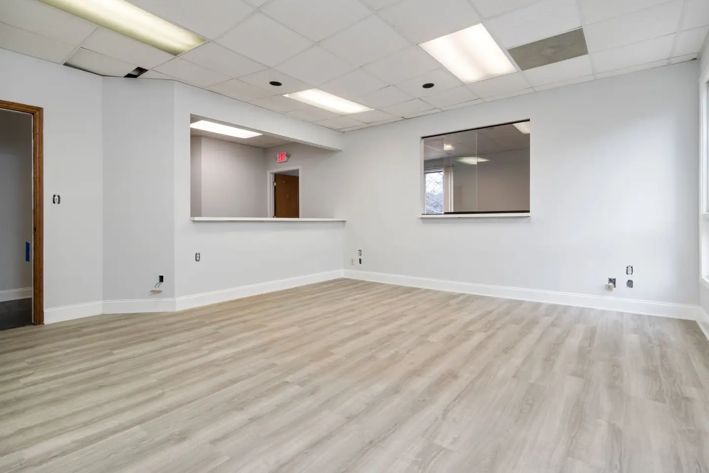 Modern and spacious empty room with wooden flooring and recessed lighting.