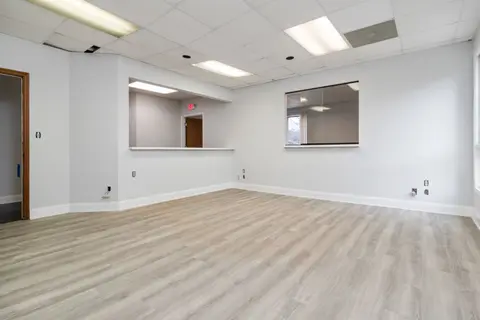 Modern and spacious empty room with wooden flooring and recessed lighting.