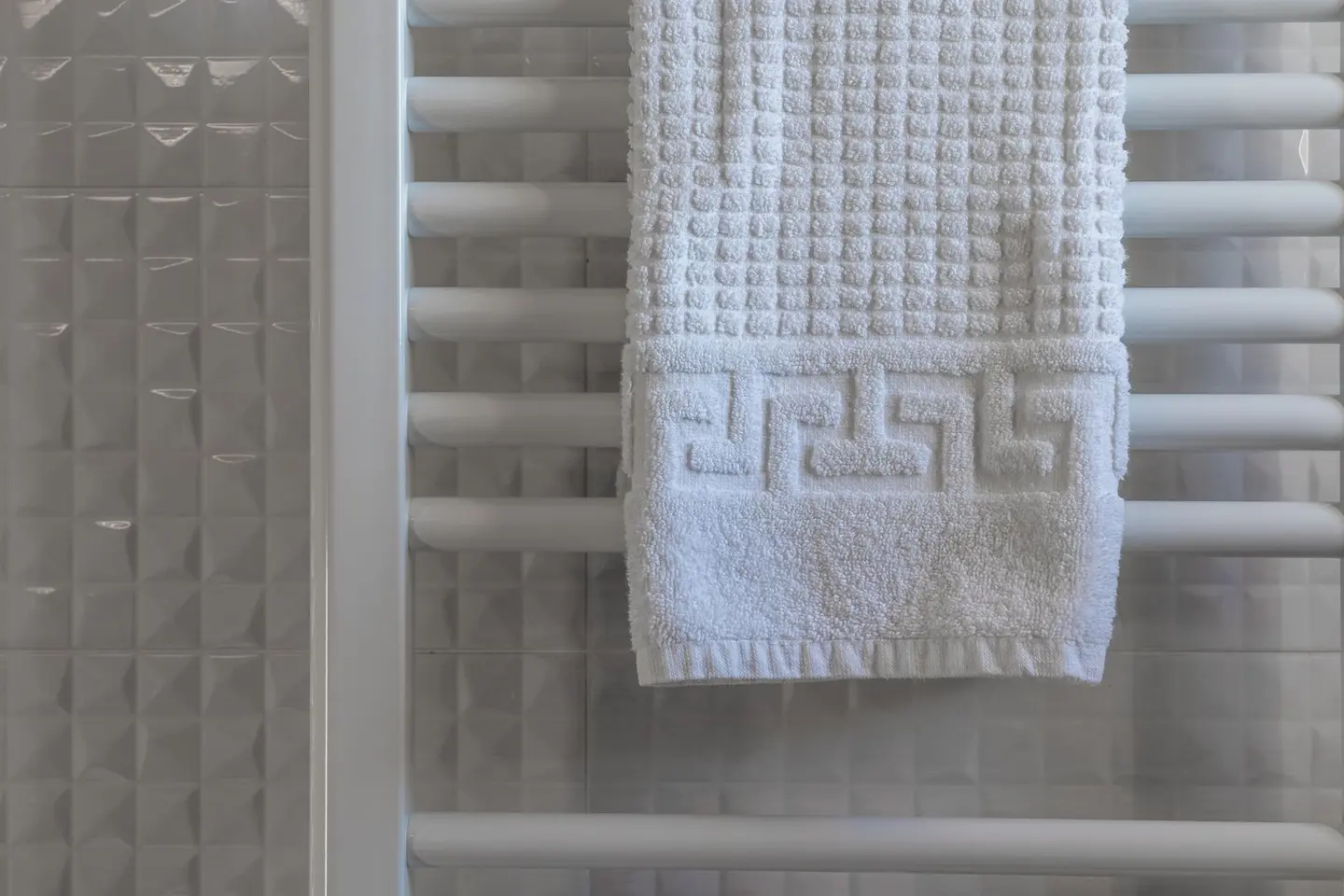 White towel on a radiator in a modern, minimalist bathroom with tiled walls.