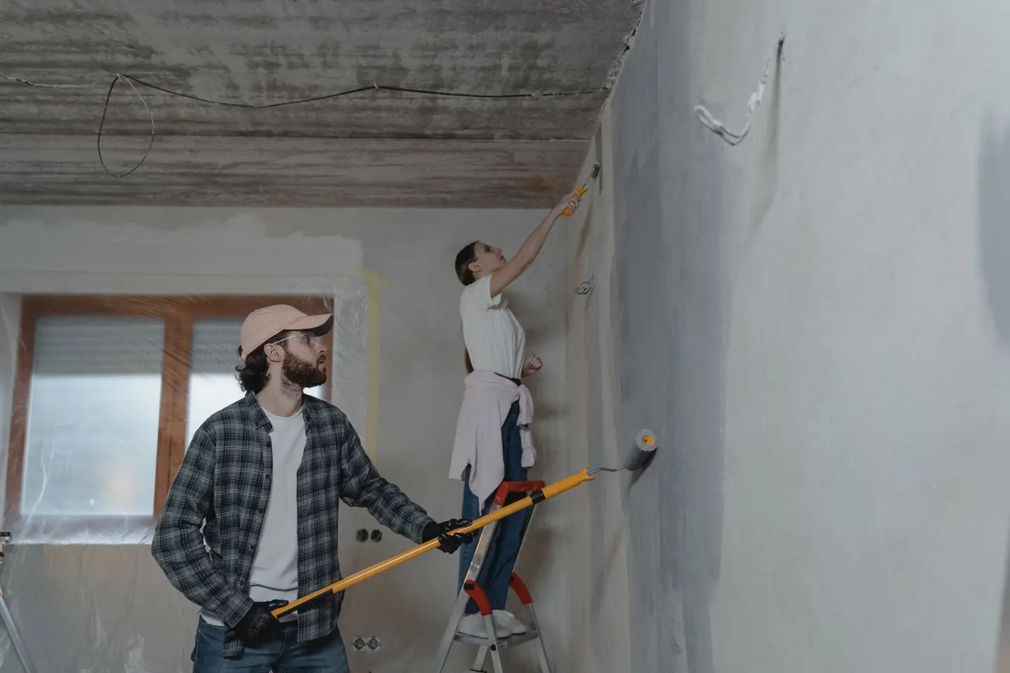 A couple painting a room together, highlighting teamwork in home renovation.