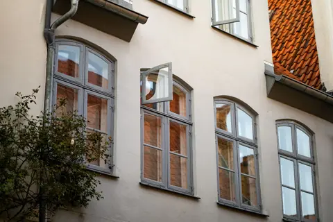 A historic building facade with open arched windows and red tiled roof.
