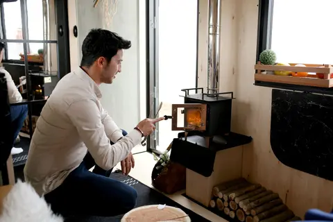 A man lights a wood hob inside a cozy room, creating a warm and inviting atmosphere.